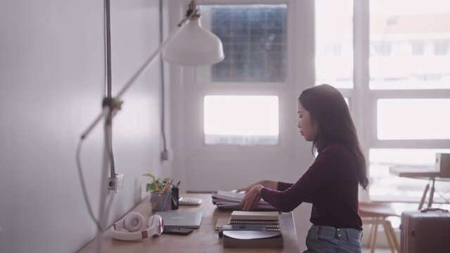 An Asian female student is in the process of organizing her belongings as she moves into her dormitory ahead of the new semester, preparing for the start of her classes.