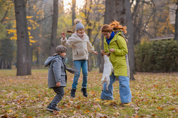 Caucasian children and red-haired woman play with dog jack russell terrier in autumn park.