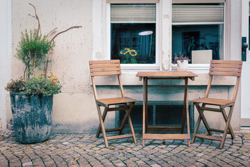 Fototapeta na wymiar Holzstühle und Tisch vor einer Hausfasade