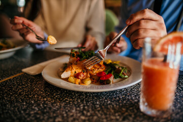 A smiling woman and man having lunch together at a busy restaurant. Focus on a food in plate