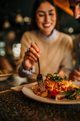 A smiling woman and man having lunch together at a busy restaurant. Focus on a food in plate