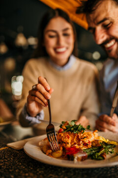 A smiling woman and man having lunch together at a busy restaurant. Focus on a food in plate