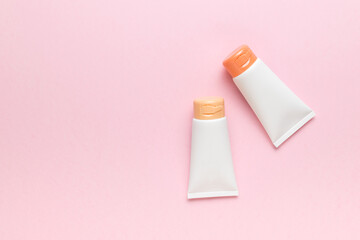 Two tubes of cream on a light pink background. A place for your text. The concept of body care.