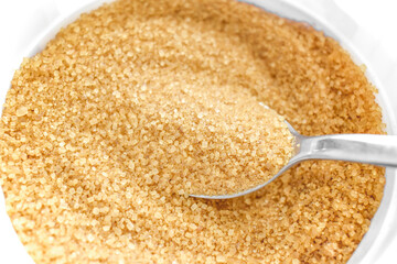 Brown sugar on spoon in plastic jar. 