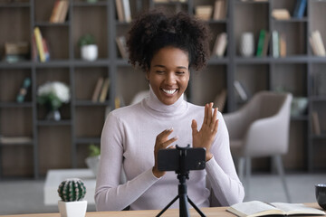 Happy young African woman, gen Z student girl, presenter speaking at webcam on mobile phone. Millennial job candidate talking to employer, recruiter passing interview via video call, conference chat - obrazy, fototapety, plakaty