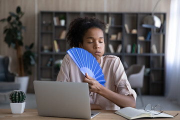 Exhausted African remote employee, student girl, business woman suffering from heat, hot stuffy...
