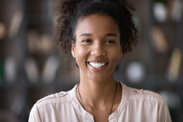 Portrait of happy young millennial African American woman, Black student girl, looking at camera with toothy smile. Screen view of employee, job candidate laughing at online job interview. Head shot