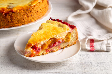 Homemade tart with yellow plums, raspberries and curd cream on a light background.