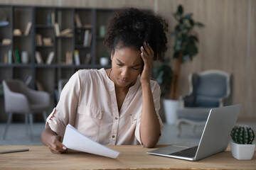 Shocked frustrated young African American woman getting document with bad news. Student girl receiving letter from college, rejection notice from university, reading paper, feeling sad, upset