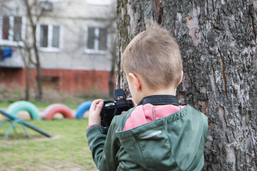 kid on the street in a jacket with an film camera