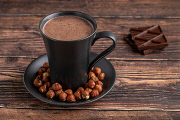 Hazelnut hot chocolate with chocolate next to it on wooden table