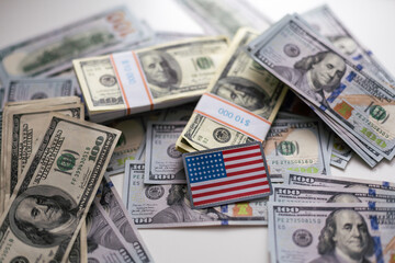 Many one hundred dollar bills are scattered on the table