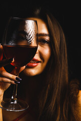 A glass of red wine in the hands of a sexy woman in a red dress