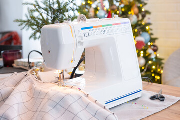 Sewing process on a sewing machine, a needle with a thread and a holder close-up stitch the white checkered fabric. Preparation for Christmas and new year, textiles for cozy in festive decor interior