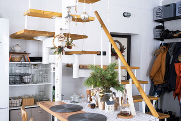 Festive Christmas decor in white kitchen, white modern loft interior with a metal modular ladder...