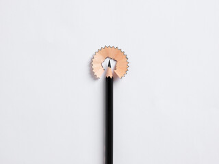 Education concept. Black pencil tip surrounded by its shaving on white background.