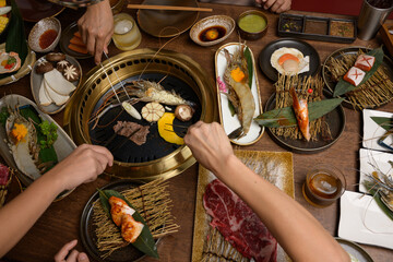 A set of grill food on a wooden table in restaurant.Fresh meat and shrim sliced for grilled menu.Party of friends or family eating dinner on wooden table background.
