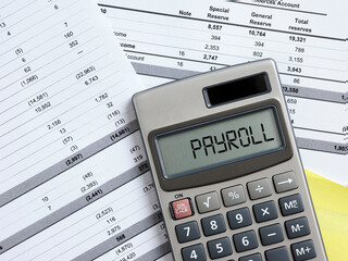 Calculating the payroll concept. Staff wages. The word payroll on a calculator. - obrazy, fototapety, plakaty