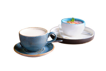 Blue cup of cappuccino coffee on a wooden table, isolated on a white background. Fruit dessert and drink in a summer cafe, close up