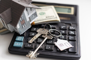 Mortgage concept. House model, calculator and money on white wooden table, closeup with space for text