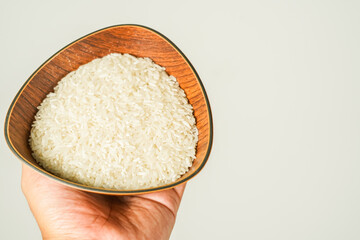 rice in a wooden bowl held by hand, zakat concept