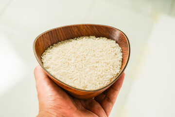 rice in a wooden bowl held by hand, zakat concept