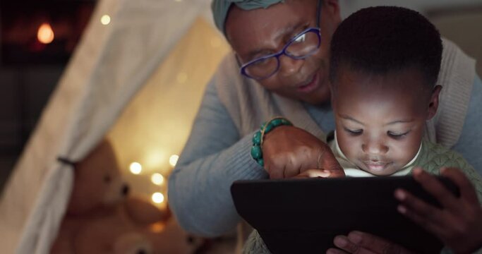 Home, tablet and family with a child at night watching a movie or video for e learning. African woman or grandmother and kid together at fort with tech for education, streaming and e book or story