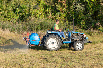 Male gardener on a Mini-tractor. Maintenance of the territory, sprays territory with insecticide...