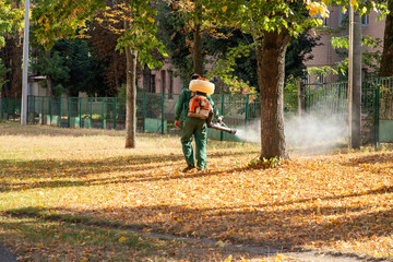 Worker sprays territory with insecticide for mosquitoes or pests or herbicides for weeds.