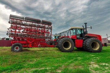 red tractor. farming machinery wheeled tractor on a green grass over farm background