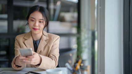 Businesswomen reading finance data of new business on smartphone to thinking analysis strategy investment and management about new startup project while checking finance data on document in workplace