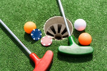 Casino chips and golf equipment on the green lawn.