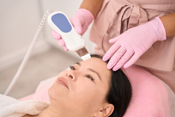 Obraz na płótnie Canvas Beautiful woman undergoing ultrasonic facial cleansing in a cosmetology salon