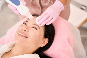 Fototapeta na wymiar Asian woman undergoing ultrasonic facial cleansing in a cosmetology salon