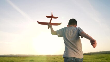 Happy family concept.child runs on the green grass with a toy airplane. holding plane in his hands. A child's dream is to become pilot. baby plays with a toy airplane in nature. child dreams of flying