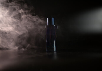men's perfume in a blue bottle on a black background with smoke