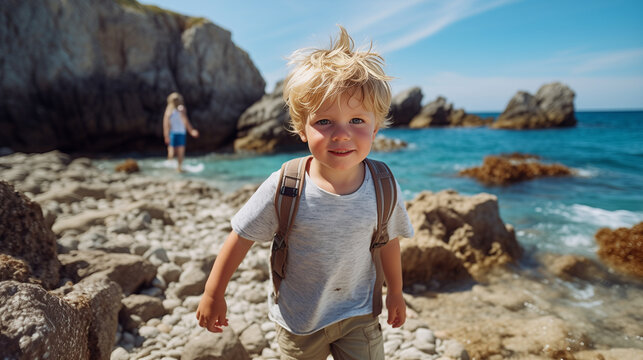 boy hiking along rocky sea coast at summer