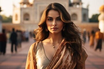 Fototapeta premium Beautiful Indian woman model in sari traditional dress with the Taj Mahal Palace in the background.