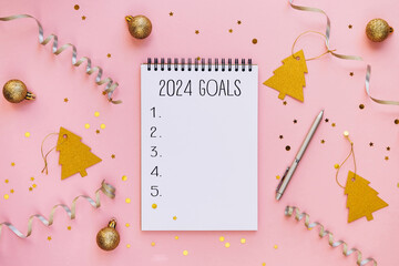 New year resolutions 2024 on desk. 2024 goals list with notebook on festive pink background....