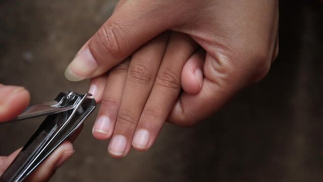 a mother's hand cutting a small child's nails