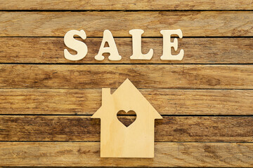 Word Sale made of wooden letters and house model on a wooden background, flat lay.