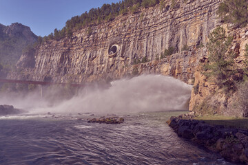 reservoir spillway in the middle of a mountain wall, large column of water