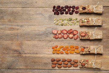 Different tasty granola bars and ingredients on wooden table, flat lay. Space for text