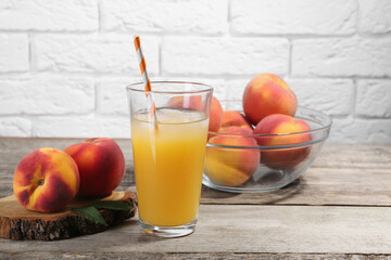 Glass of delicious peach juice with ice and fresh fruits on wooden table