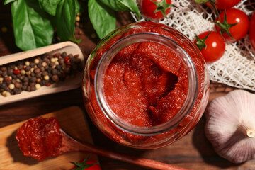 Jar of tasty tomato paste and ingredients on table, flat lay