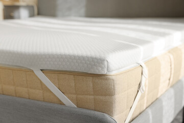 Fototapeta na wymiar White memory foam mattress topper on grey bed, closeup