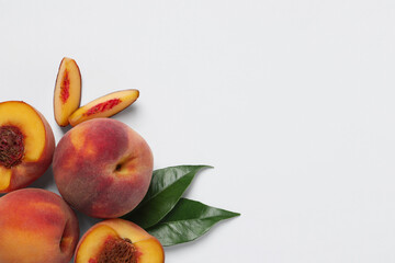 Cut and whole fresh ripe peaches with green leaves on white background, flat lay. Space for text