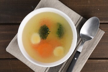 Tasty soup with vegetables in bowl served on wooden table, top view