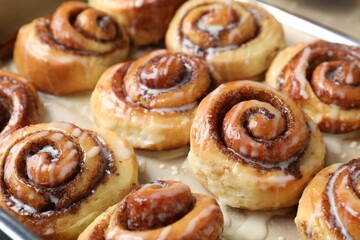 Tasty cinnamon rolls with cream on parchment paper, closeup