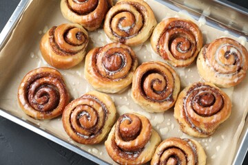 Fototapeta premium Baking dish with tasty cinnamon rolls on dark table, top view